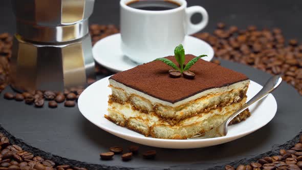 Portion of Traditional Italian Tiramisu dessert, cup of espresso, mocha and coffee beans alt