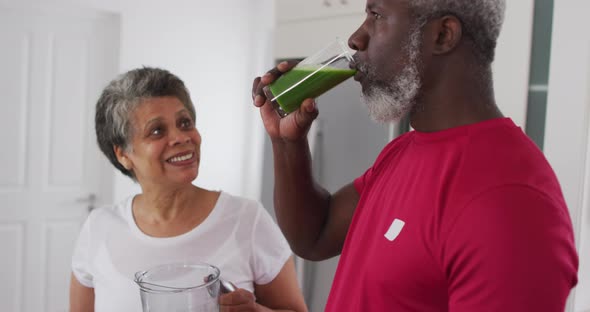 Senior african american man and woman drinking fruit and vegetable health drinks at home alt