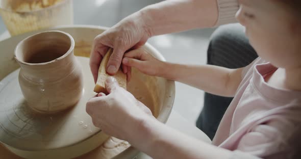 Grandmother Teaches Her Granddaughter Working on a Pottery Rotating Wheel alt