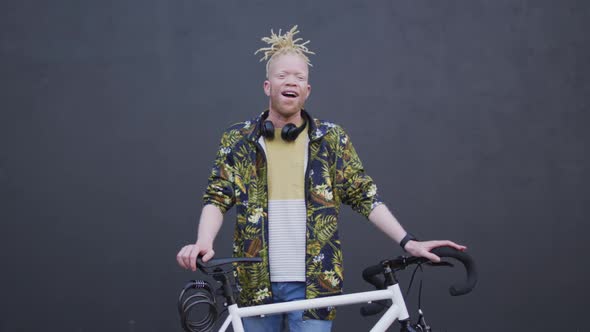 Portrait of smiling albino african american man with dreadlocks looking at camera with bike alt