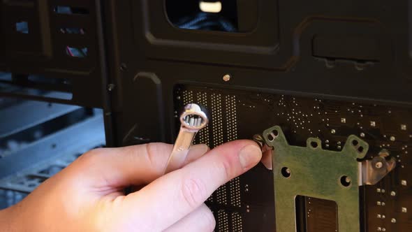 Male hand with metal wrench fix nut on bolt at computer motherboard