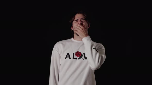 Trendy Young Man yawning extremely, tired gesture, wide, black background alt