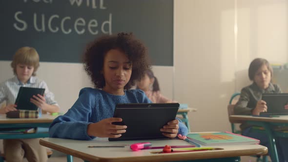 Smiling African American Girl Using Digital Tablet in Class with Classmates alt