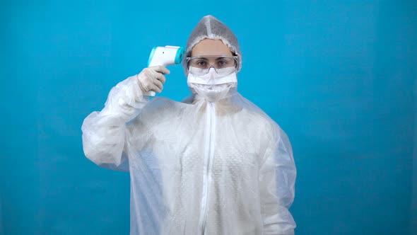 Young Woman in a Protective Suit with an Infrared Thermometer. The Girl Measures the Temperature alt