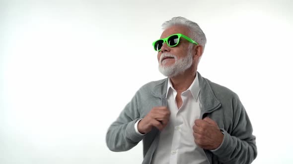 Stylish Emotional Old Man Pensioner with a Gray Beard in Green Glasses Dances with Funny Emotions on