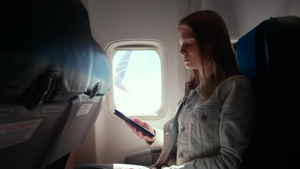 Young Woman Reads Ebook While Flying in Airplane