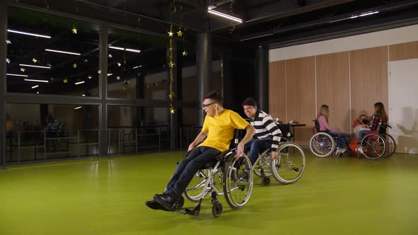 Joyful Teen Boys Having Fun Racing in Wheelchairs alt