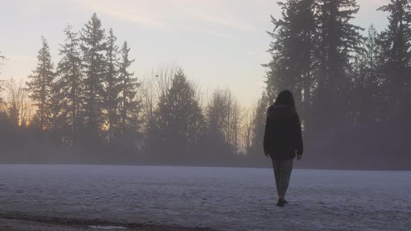 Girl Walking in a Park During Foggy Winter Sunrise alt