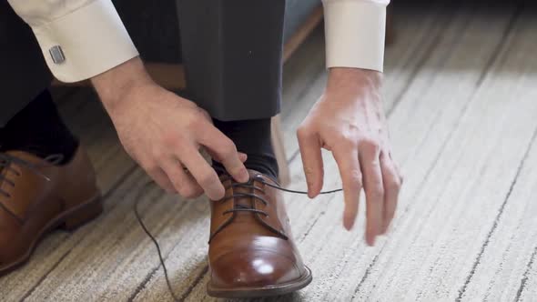 The Man is Tying the Laces on His Shoes alt