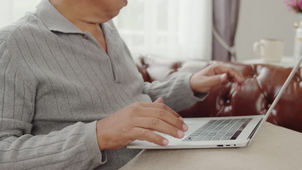 Senior man typing chatting on laptop computer at home