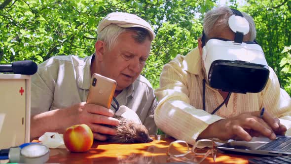 Aged Man with Magnifying Glass Holds Hedgehog Near Senior alt