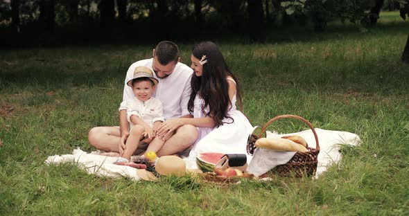 Cheerful Caucasian Mum, Dad and Their Child Have Fun Together and Smiles in the Garden