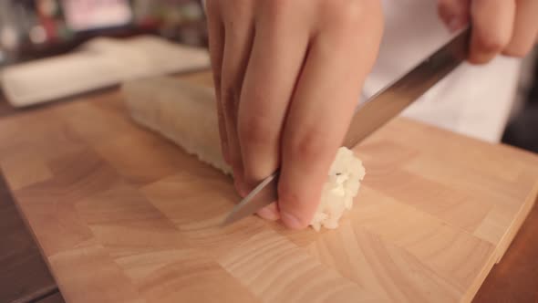 Cook Cuts Prepared Roll with Knife and Removes the Piece to Side Closeup alt