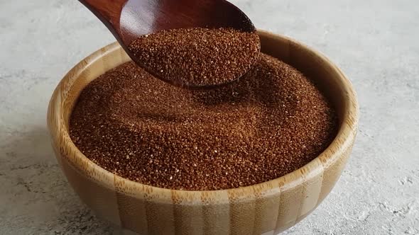 Raw teff grain in a wooden bowl close up alt