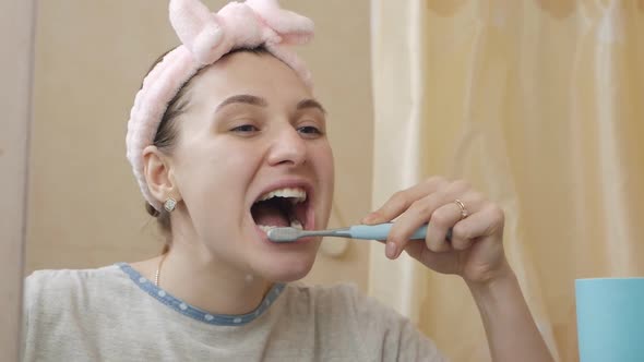 Young Woman Brushing Teeth in Bathroom