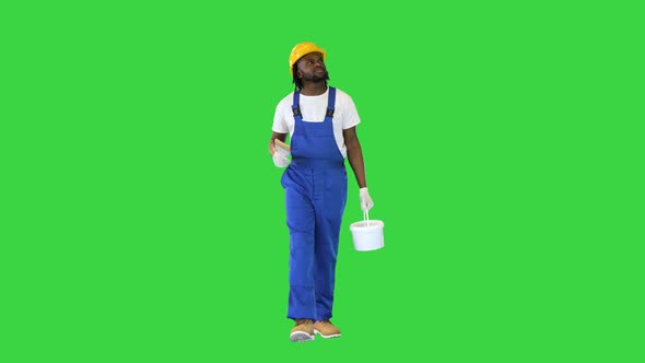 Man Holding a Paint Brush and a Paint Bucket Walking and Looking Around What to Paint on a Green