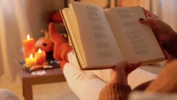 Young Woman Reading Book at Home on Halloween alt