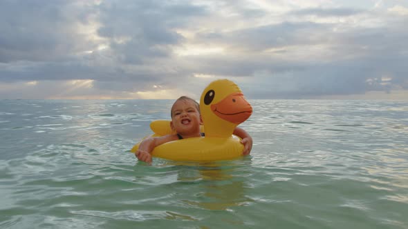 Adorable Baby Girl Swimming with Inflatable Duck in Indian Ocean alt