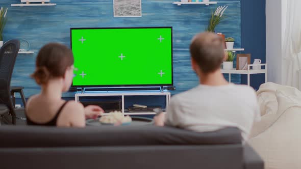 Couple Sharing a Bowl of Popcorn While Watching Tv and Switching Channels Looking at Green Screen alt