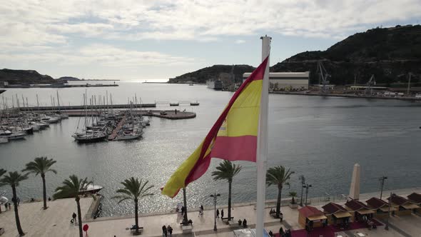 Aerial view of Spanish flag streaming in breeze, historic Cartagena marina