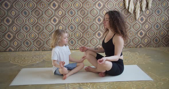 Modern Happy Healthy Family Kid Son and Young Mother Having Fun Doing Yoga Exercises Together Sit in