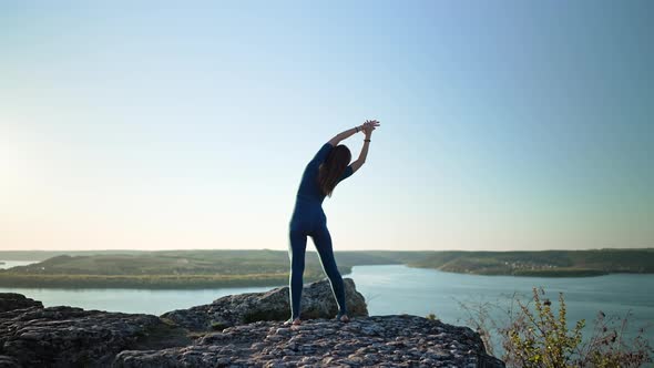 Silhouette of Yogi Woman Beginning Yoga Practice on Top of Rock on High Mountain alt