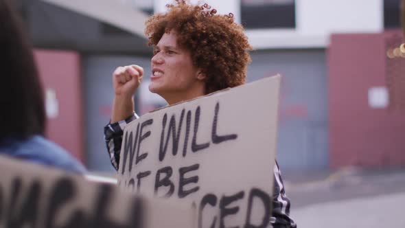 Diverse group of men and women holding placards shouting raising fists during protest alt