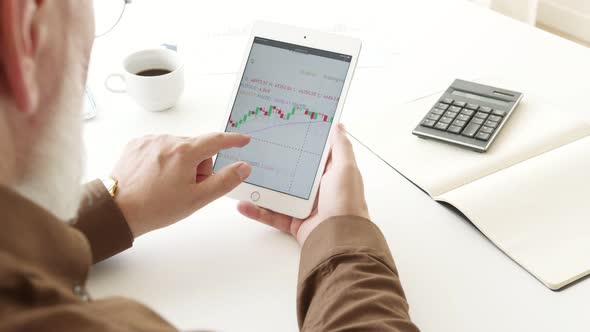 tablet with stock market charts on a white table alt