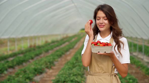 Cute Woman Smiling and Admiring Fresh Tasty Strawberry alt