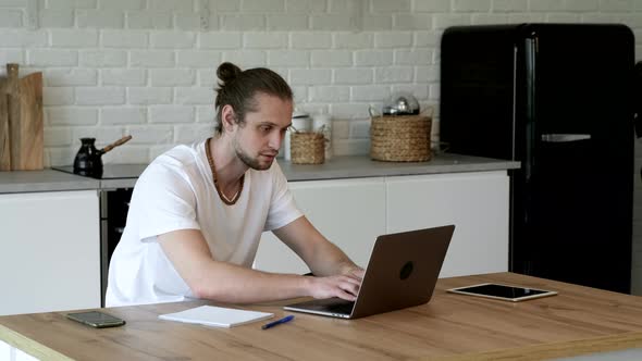 Side view handsome young businessman in eyewear working with computer remotely, sitting alt