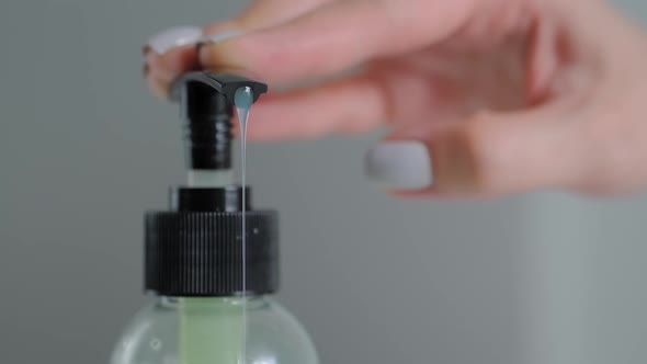 Slow Motion: Woman Pushing Dispenser, Squeezing Out Antiseptic Gel - Close Up alt