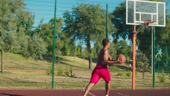 Shirtless Basketball Player Slam Dunking at Court alt