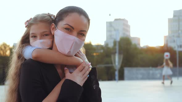 Woman in Medical Mask, Mother Holds Child in Hands on Back on Street Walk in Coronavirus Epidemic alt