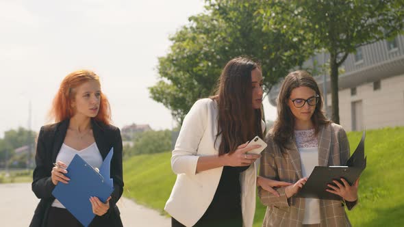 Business Ladies Walking in the Park with Mobile Gadgets in Their Hands Smiling and Talking. Business alt