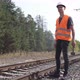 The railway worker stands along the railway tracks, holding a sledgehammer in his hands. - VideoHive Item for Sale