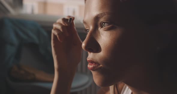 Blonde girl in front of the mirror putting on make up alt
