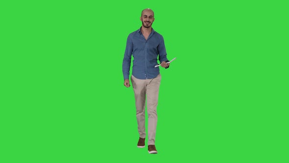 Arab Presenter Walking with Digital Tablet Swiping Pages on It on a Green Screen, Chroma Key alt