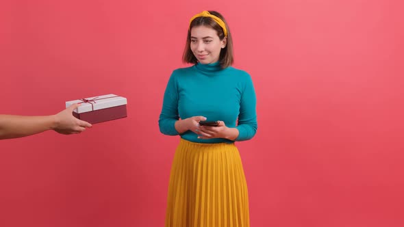 Happy Young Woman Receiving a Gift While Browsing in Smartphone alt