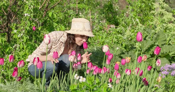 Young Beautiful Girl in Hat, Works in the Garden, Cares for Flowers. Woman Farmer Works at Cottage