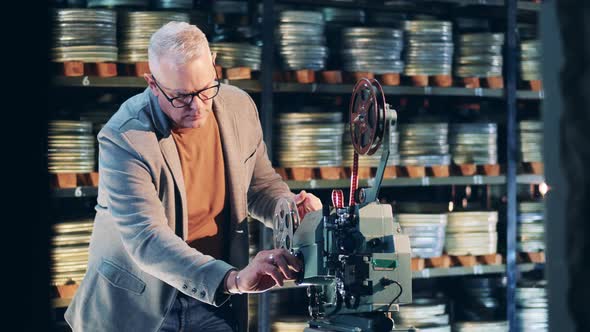 Antique Film Projector is Getting Operated By an Archive Specialist alt