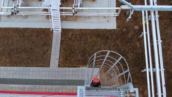 An Oil and Gas Worker Climbs a Metal Ladder to the Roof for Inspection alt
