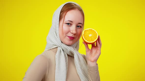 Portrait of Redhead Beautiful Slim Woman Holding Cuted Half of Orange Looking at Camera alt