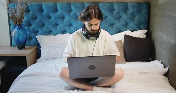 Freelancer Sitting on Bed with Laptop