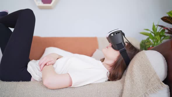 A Woman Rests on the Couch in a Virtual Reality Headset