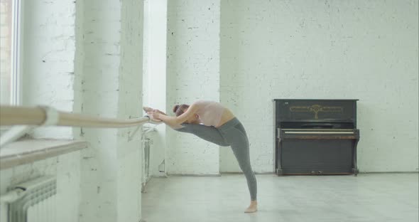 Elegant Girl Doing Leg Stretching Exercise at Barre alt