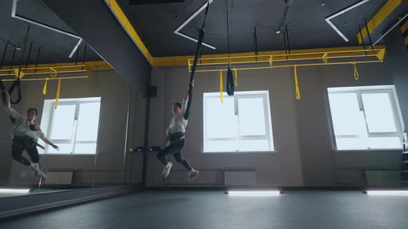 Acrobatic Training in Fitness Club Woman is Hanging on TRX System Running and Whirling in Air alt