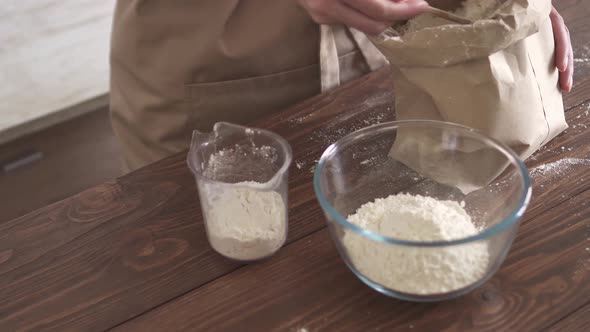 Preparing cake dough. Chef in apron prepares  ingredients for tart. Women's hands pour flour in cup alt