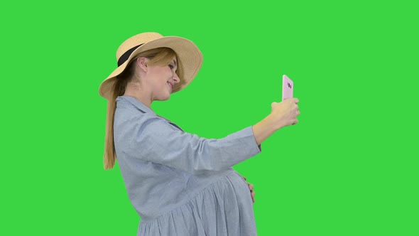 Charming Pregnant Woman in a Hat Making Selfie on a Green Screen, Chroma Key alt