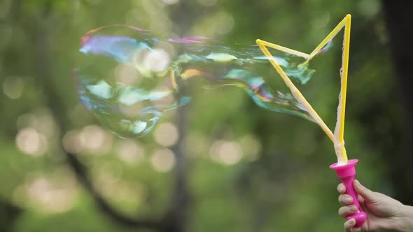 Female Hand Holding Blowing Shimmering Soap Air Bubble Close-up Slow Motion