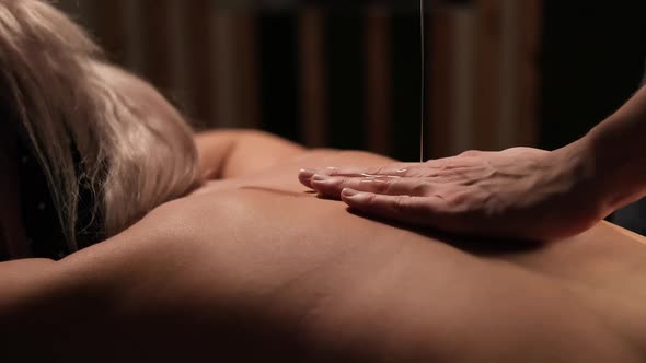 Masseur Hands Pouring Massaging Oil to Female Back Preparing to Massage alt